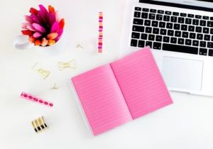 pink notebook on desk with laptop & pens